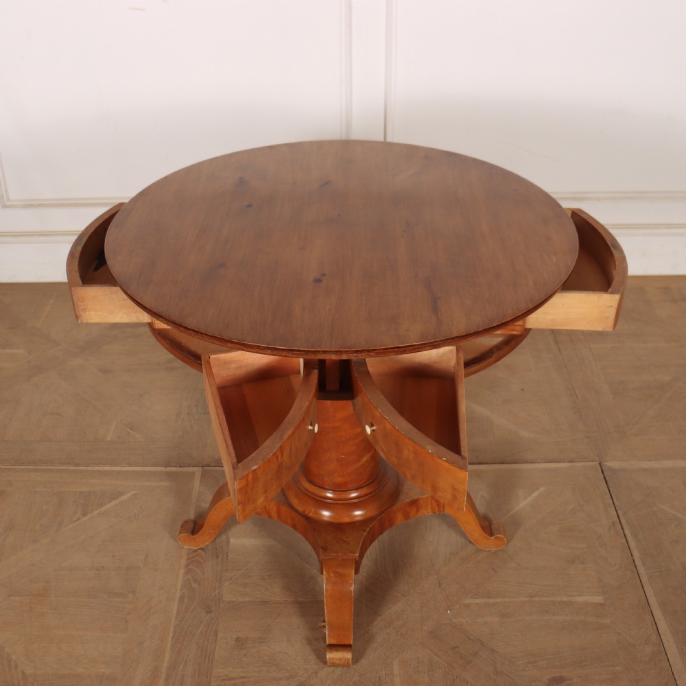 A 19th-century Swedish Biedermeier drum table in satin birch with a circular top, frieze drawers, central pedestal column, and four splayed legs. View II