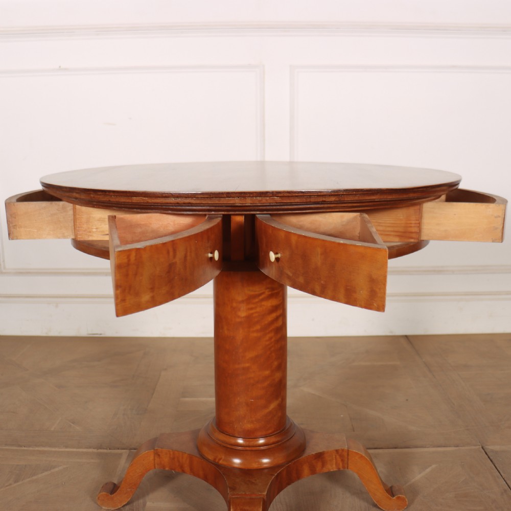 A 19th-century Swedish Biedermeier drum table in satin birch with a circular top, frieze drawers, central pedestal column, and four splayed legs. View III