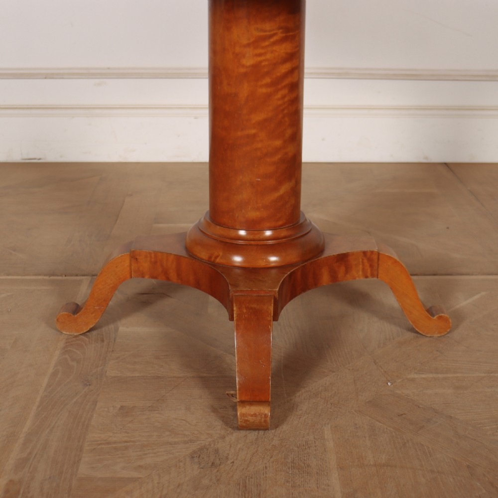 A 19th-century Swedish Biedermeier drum table in satin birch with a circular top, frieze drawers, central pedestal column, and four splayed legs. View IV
