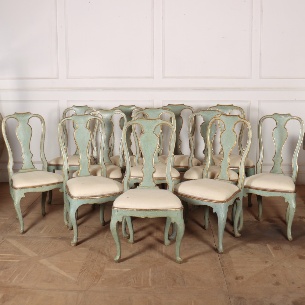 A set of twelve 18th-century Italian Rococo side chairs with pale green painted frames, parcel-gilt detailing, and cream upholstered seats.
