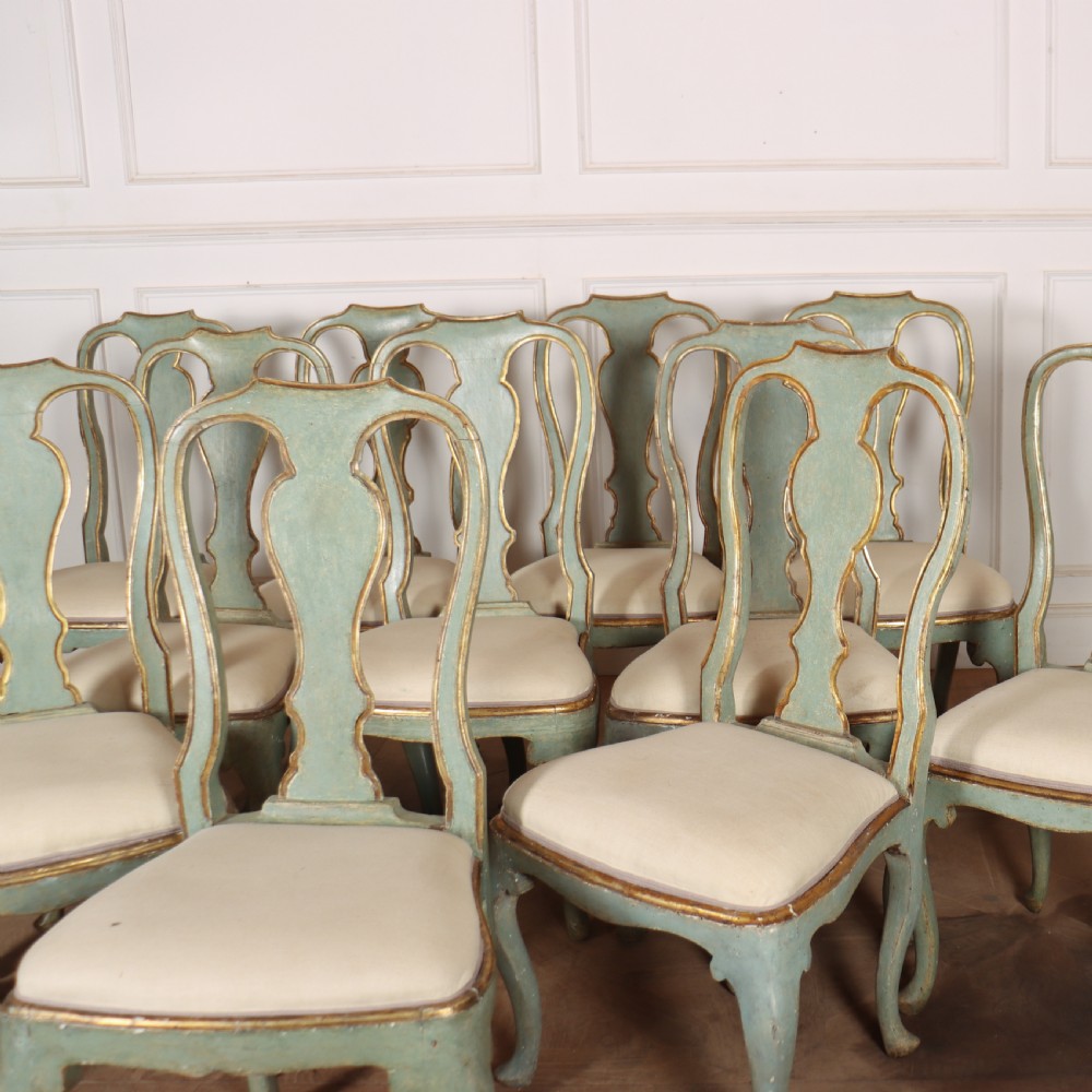 A set of twelve 18th-century Italian Rococo side chairs with pale green painted frames, parcel-gilt detailing, and cream upholstered seats. View II