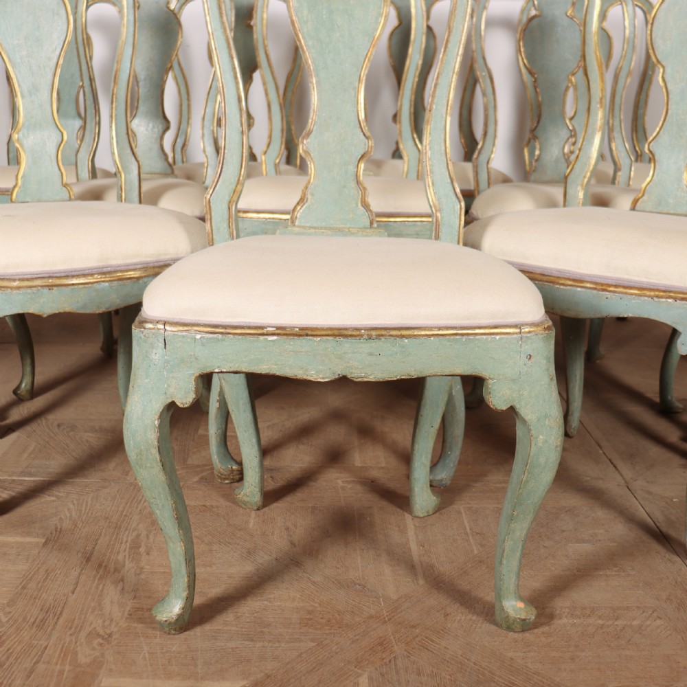 A set of twelve 18th-century Italian Rococo side chairs with pale green painted frames, parcel-gilt detailing, and cream upholstered seats. View IV