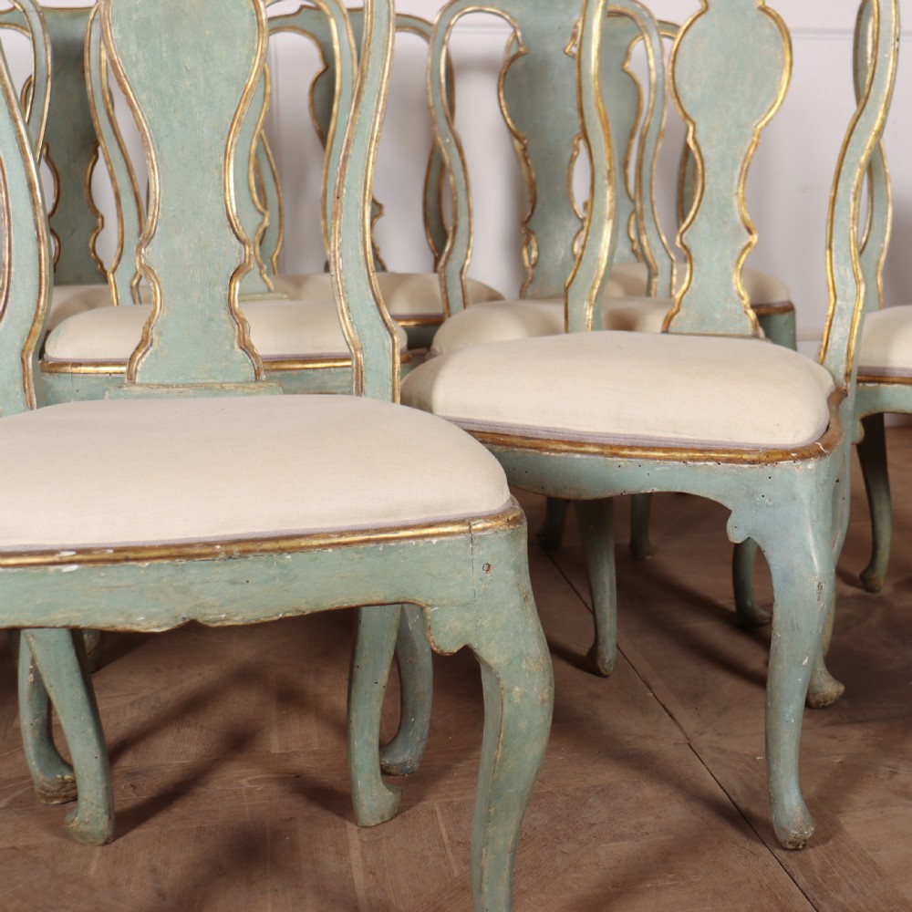 A set of twelve 18th-century Italian Rococo side chairs with pale green painted frames, parcel-gilt detailing, and cream upholstered seats. View VI