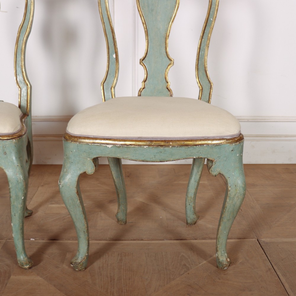 A set of twelve 18th-century Italian Rococo side chairs with pale green painted frames, parcel-gilt detailing, and cream upholstered seats. View X