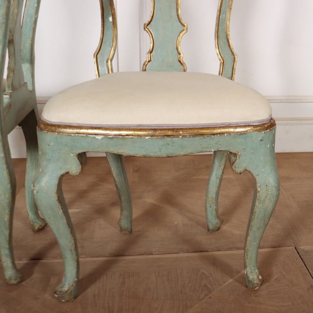 A set of twelve 18th-century Italian Rococo side chairs with pale green painted frames, parcel-gilt detailing, and cream upholstered seats. View XII