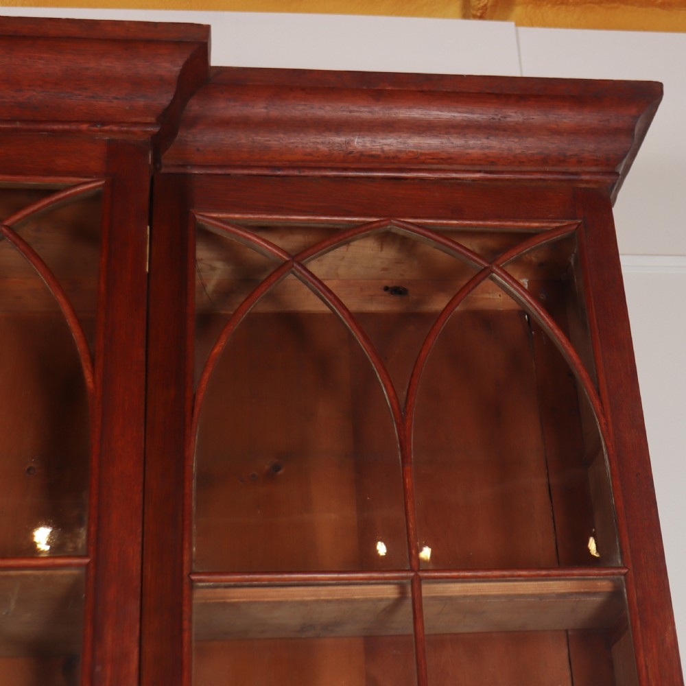 An early 19th-century mahogany breakfront bookcase featuring four glazed doors with Gothic pointed arch tracery over four matching panelled base doors. View VI