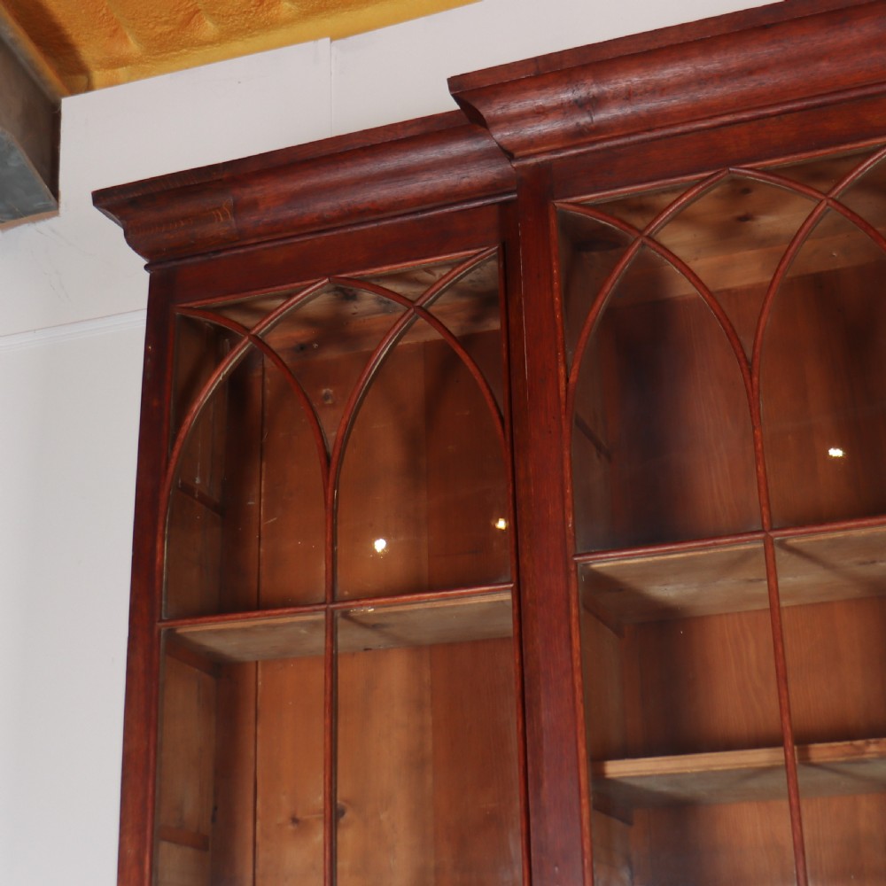 An early 19th-century mahogany breakfront bookcase featuring four glazed doors with Gothic pointed arch tracery over four matching panelled base doors. View VII