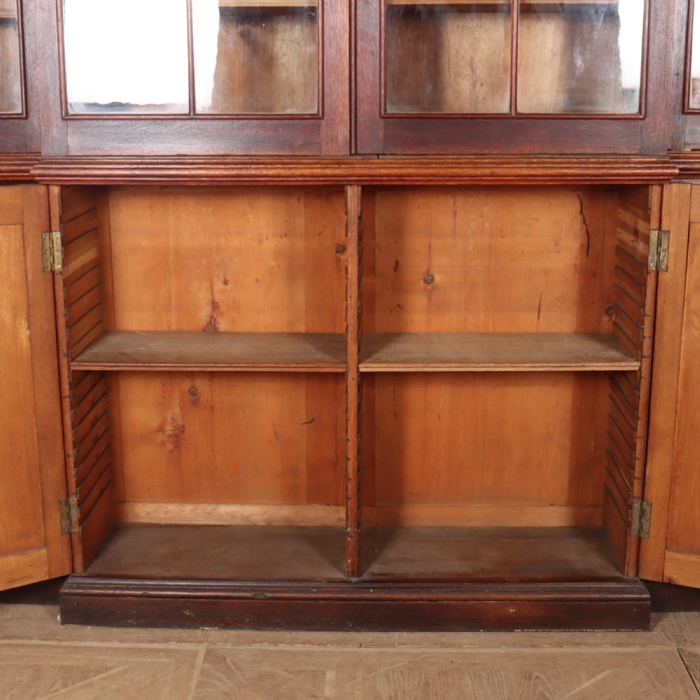An early 19th-century mahogany breakfront bookcase featuring four glazed doors with Gothic pointed arch tracery over four matching panelled base doors. View X