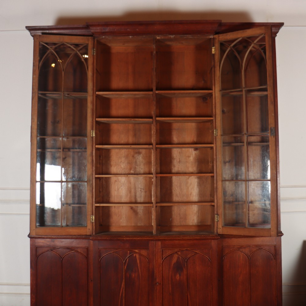 An early 19th-century mahogany breakfront bookcase featuring four glazed doors with Gothic pointed arch tracery over four matching panelled base doors. View XII