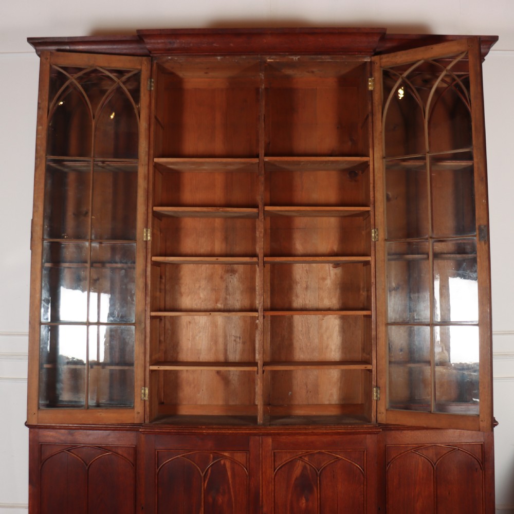 An early 19th-century mahogany breakfront bookcase featuring four glazed doors with Gothic pointed arch tracery over four matching panelled base doors. View XIII