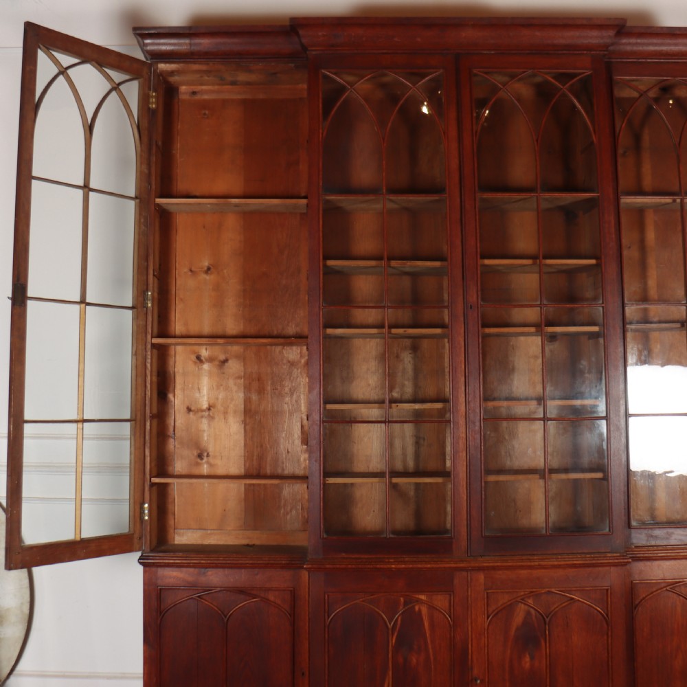 An early 19th-century mahogany breakfront bookcase featuring four glazed doors with Gothic pointed arch tracery over four matching panelled base doors. View XIV