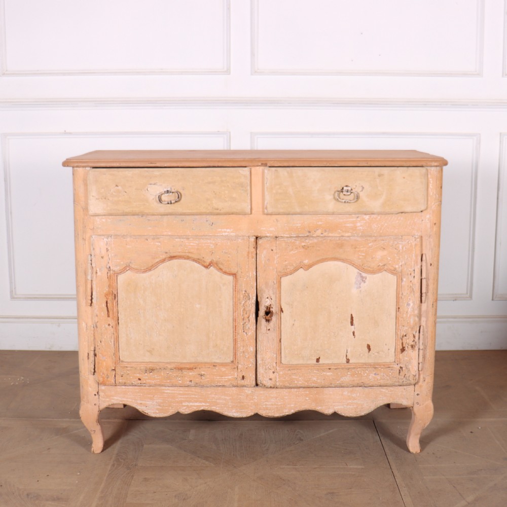 An 18th-century French provincial buffet featuring a distressed beige painted finish, two drawers, two carved panel cupboard doors, and short cabriole legs.