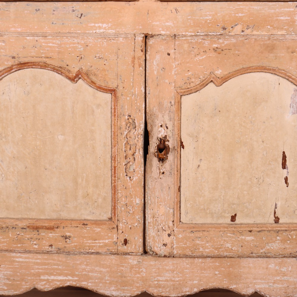 An 18th-century French provincial buffet featuring a distressed beige painted finish, two drawers, two carved panel cupboard doors, and short cabriole legs. View VI