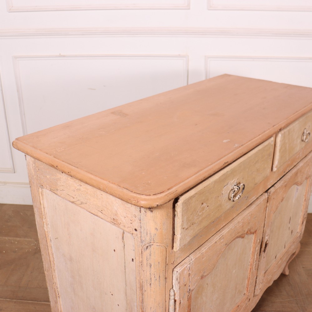 An 18th-century French provincial buffet featuring a distressed beige painted finish, two drawers, two carved panel cupboard doors, and short cabriole legs. View IX