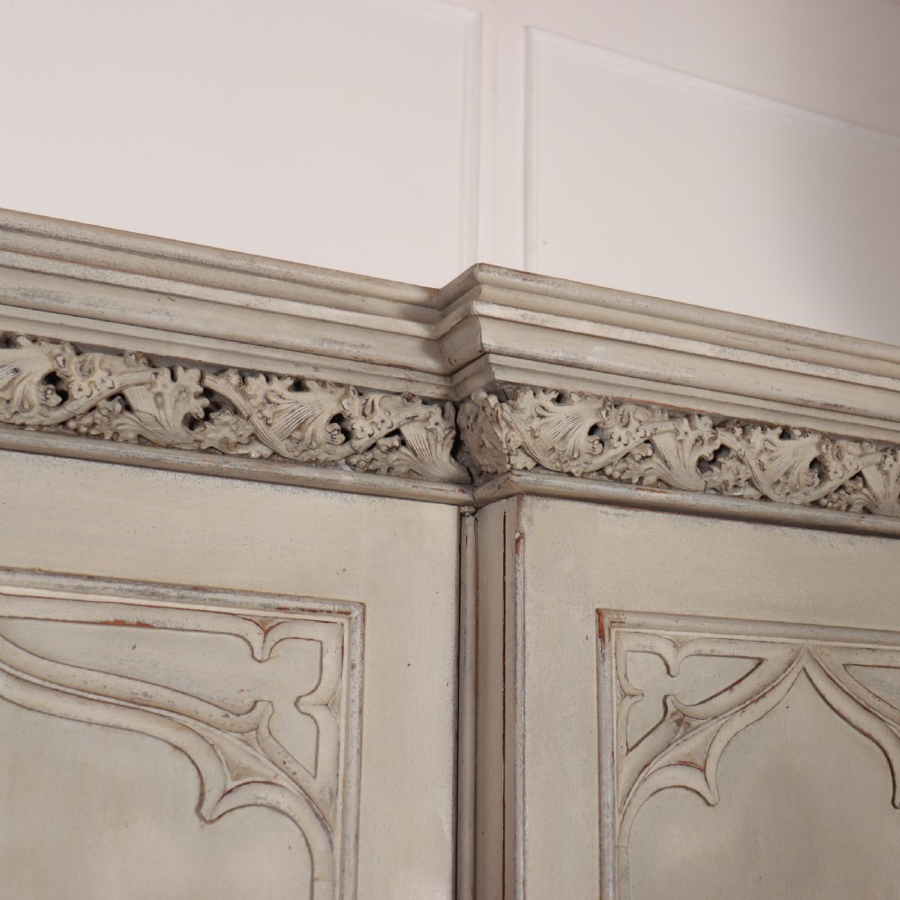 A large 19th-century painted wooden three-door wardrobe featuring carved Gothic arches and a detailed crown moulding cornice. View IV