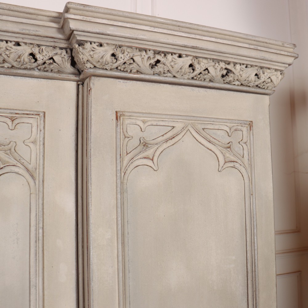 A large 19th-century painted wooden three-door wardrobe featuring carved Gothic arches and a detailed crown moulding cornice. View V