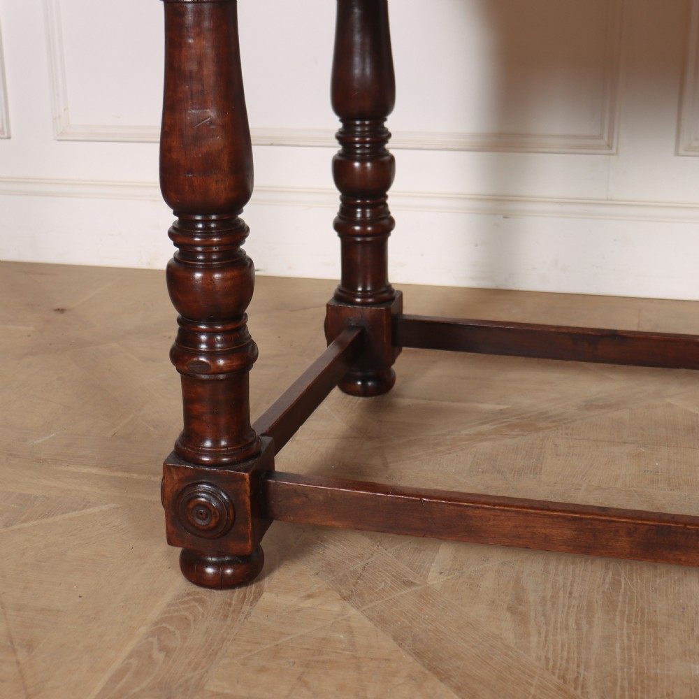 A 19th-century Italian dark walnut writing desk featuring turned legs, a carved frieze, a single central drawer, and a rectangular stretcher base. View III