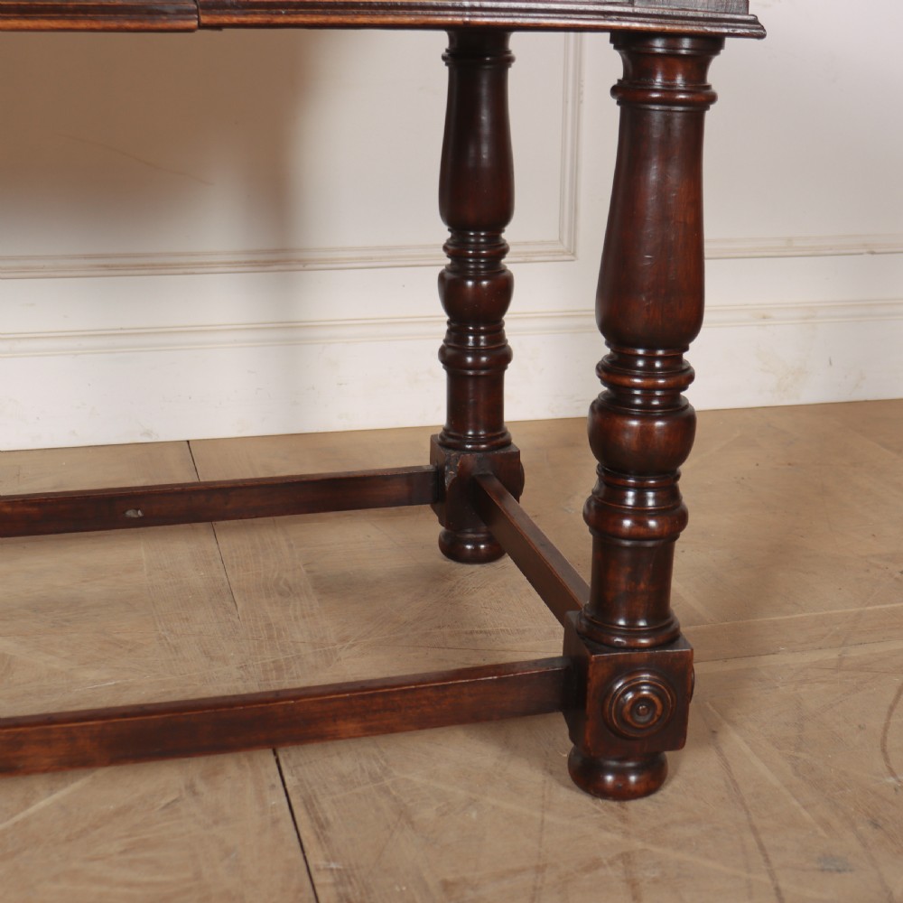 A 19th-century Italian dark walnut writing desk featuring turned legs, a carved frieze, a single central drawer, and a rectangular stretcher base. View VI