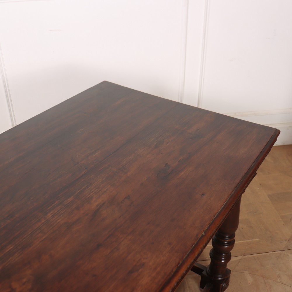 A 19th-century Italian dark walnut writing desk featuring turned legs, a carved frieze, a single central drawer, and a rectangular stretcher base. View X