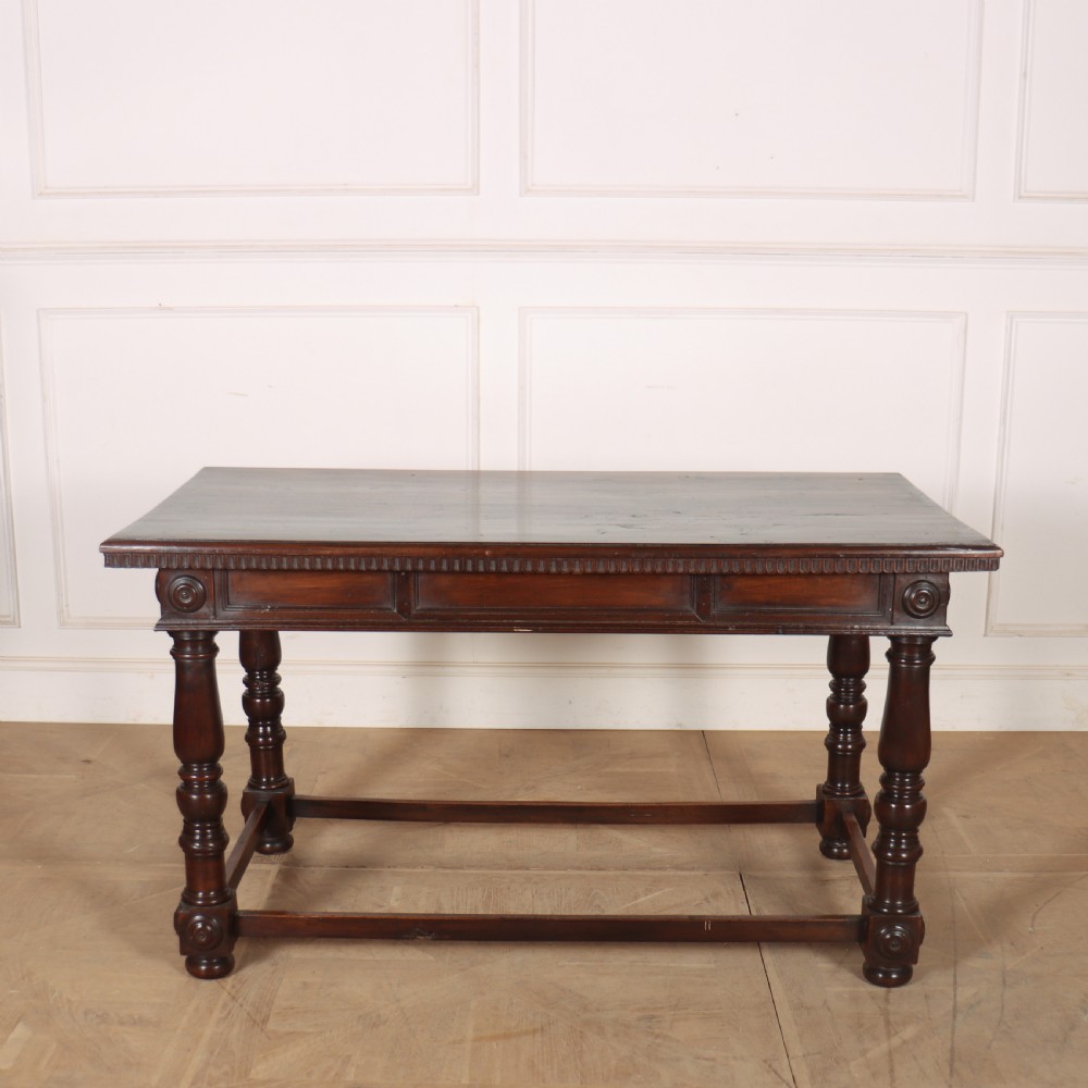 A 19th-century Italian dark walnut writing desk featuring turned legs, a carved frieze, a single central drawer, and a rectangular stretcher base. View XI