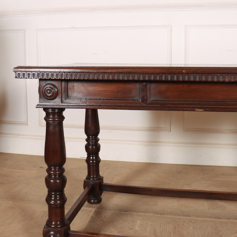 A 19th-century Italian dark walnut writing desk featuring turned legs, a carved frieze, a single central drawer, and a rectangular stretcher base. View XII