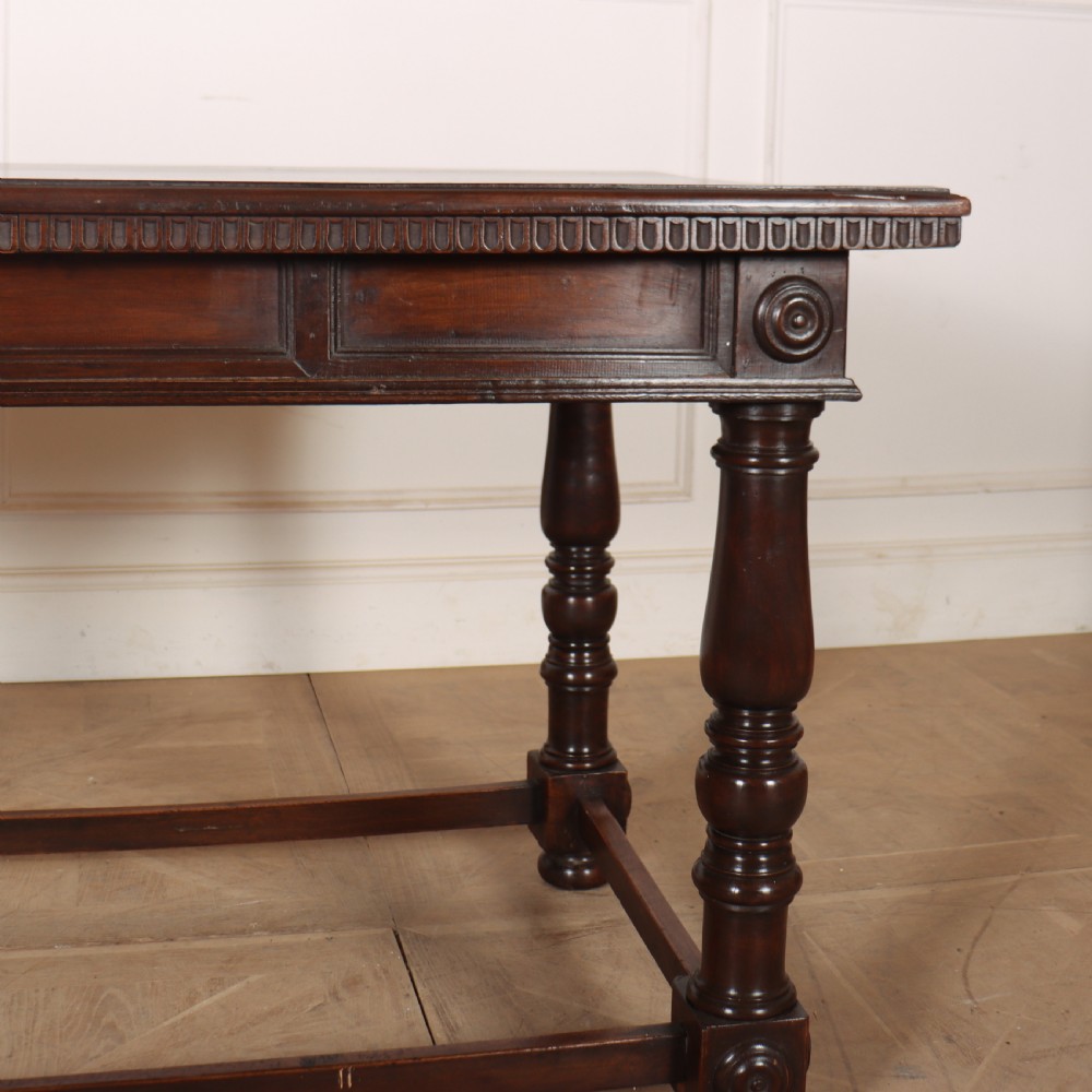 A 19th-century Italian dark walnut writing desk featuring turned legs, a carved frieze, a single central drawer, and a rectangular stretcher base. View XIII