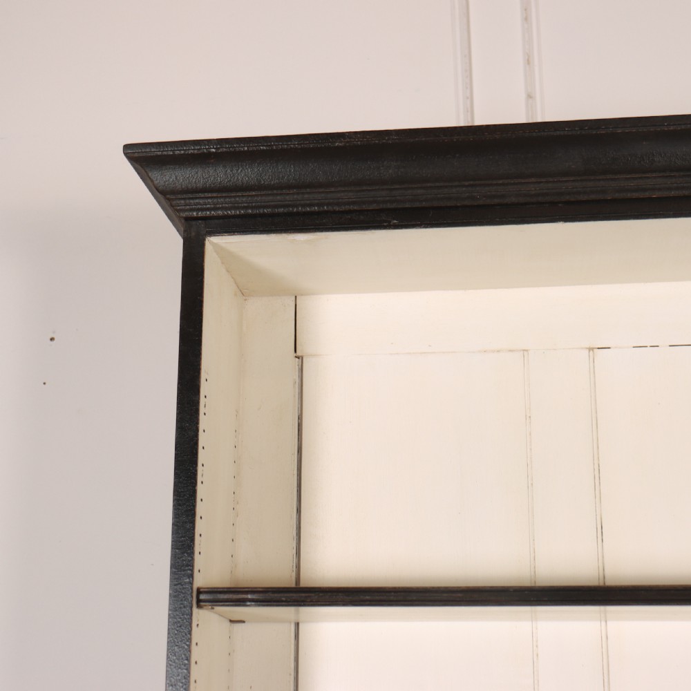 A 19th-century English painted open bookcase featuring a dark exterior, contrasting off-white interior shelves, and a lower two-door cupboard. View II