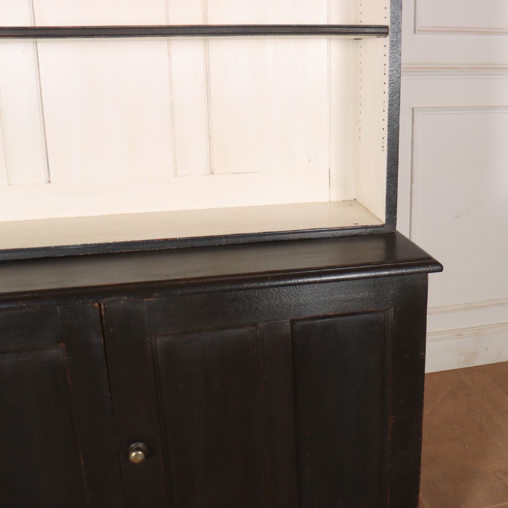 A 19th-century English painted open bookcase featuring a dark exterior, contrasting off-white interior shelves, and a lower two-door cupboard. View III