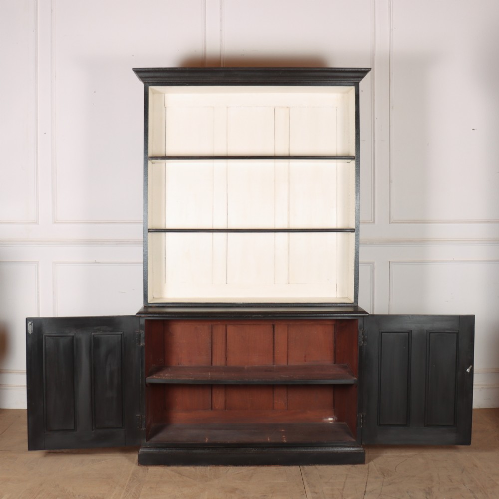 A 19th-century English painted open bookcase featuring a dark exterior, contrasting off-white interior shelves, and a lower two-door cupboard. View XI