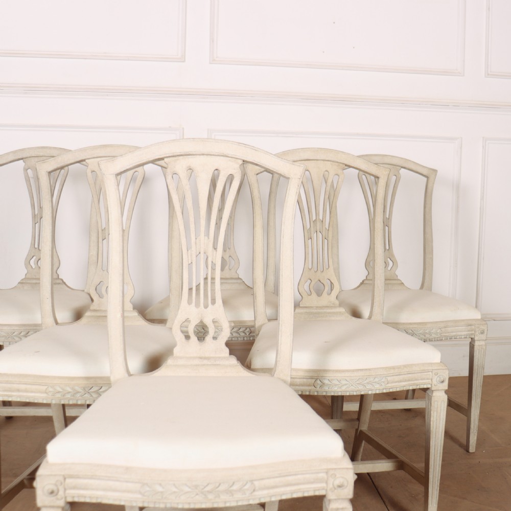 A set of six Gustavian style dining chairs painted in distressed off-white with carved splat backs and white upholstered seats. View II