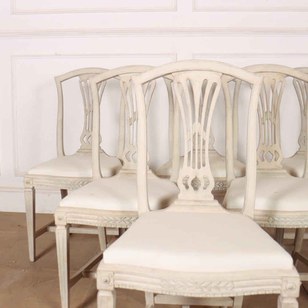 A set of six Gustavian style dining chairs painted in distressed off-white with carved splat backs and white upholstered seats. View III