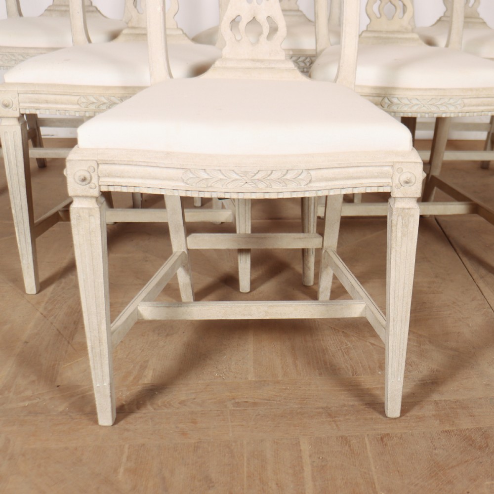 A set of six Gustavian style dining chairs painted in distressed off-white with carved splat backs and white upholstered seats. View IV
