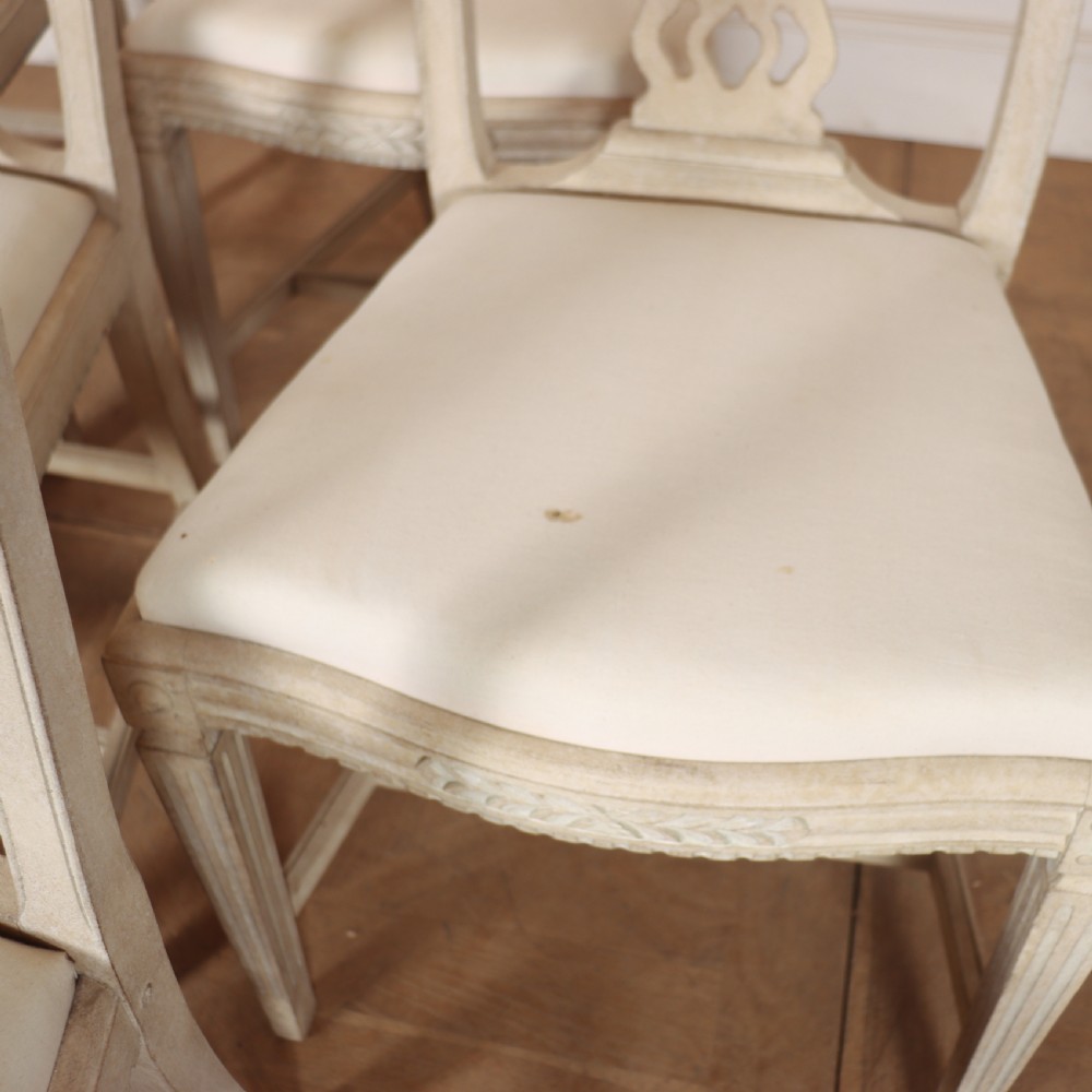 A set of six Gustavian style dining chairs painted in distressed off-white with carved splat backs and white upholstered seats. View V