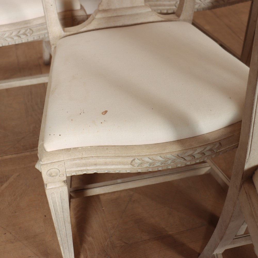 A set of six Gustavian style dining chairs painted in distressed off-white with carved splat backs and white upholstered seats. View VI