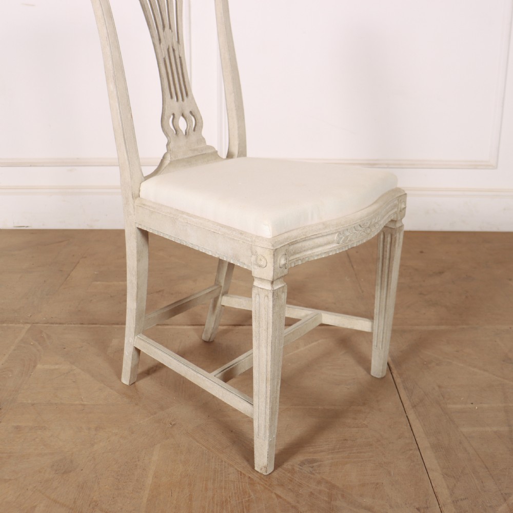 A set of six Gustavian style dining chairs painted in distressed off-white with carved splat backs and white upholstered seats. View IX