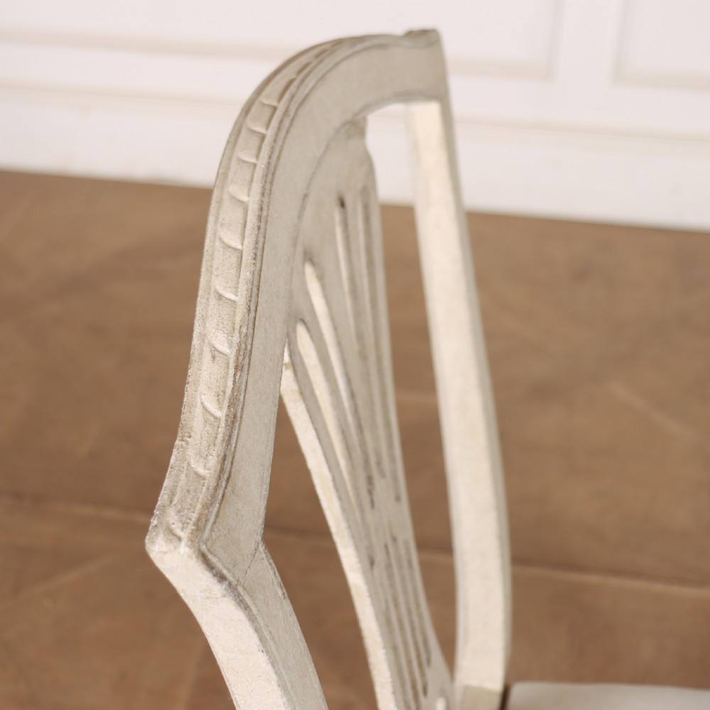 A set of six Gustavian style dining chairs painted in distressed off-white with carved splat backs and white upholstered seats. View XII