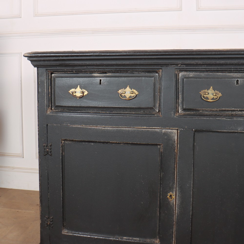 An 18th-century English country dresser base featuring a dark painted finish, three top drawers with brass handles, and three cupboard doors below. View III
