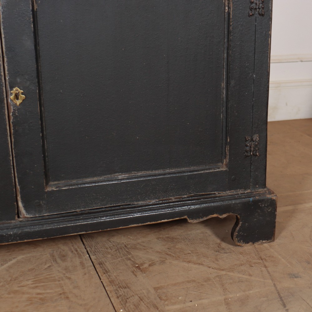 An 18th-century English country dresser base featuring a dark painted finish, three top drawers with brass handles, and three cupboard doors below. View VI