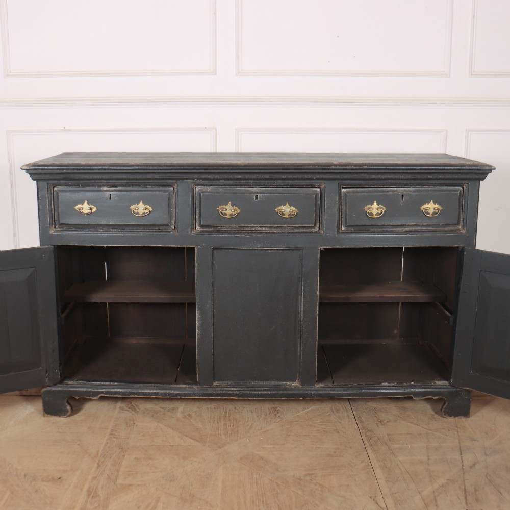 An 18th-century English country dresser base featuring a dark painted finish, three top drawers with brass handles, and three cupboard doors below. View VII