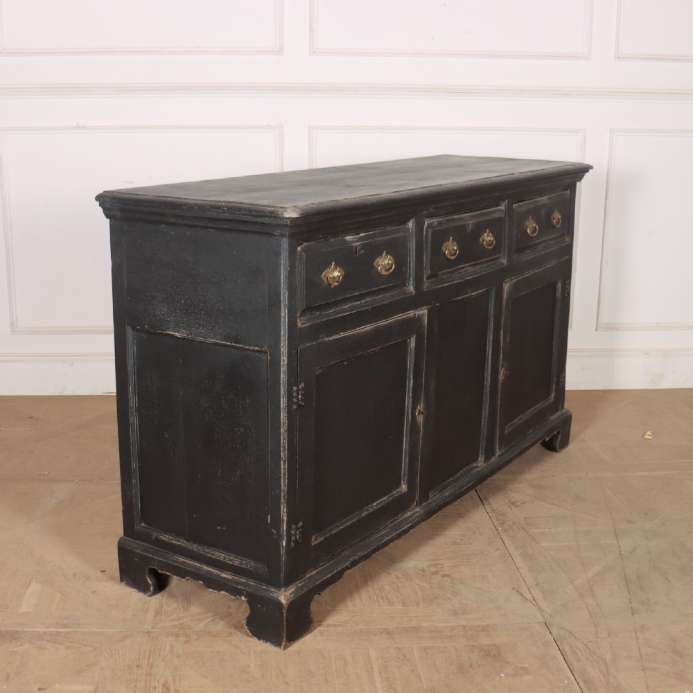 An 18th-century English country dresser base featuring a dark painted finish, three top drawers with brass handles, and three cupboard doors below. View VIII