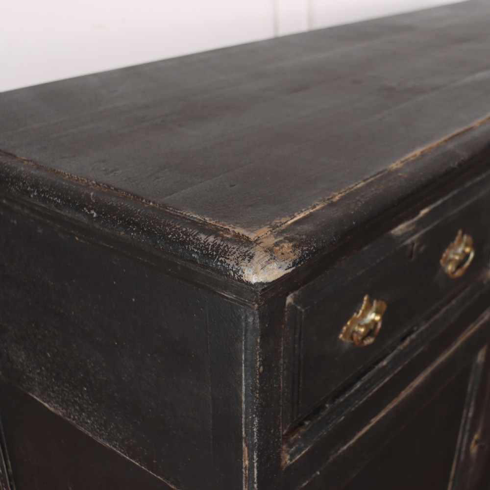 An 18th-century English country dresser base featuring a dark painted finish, three top drawers with brass handles, and three cupboard doors below. View IX