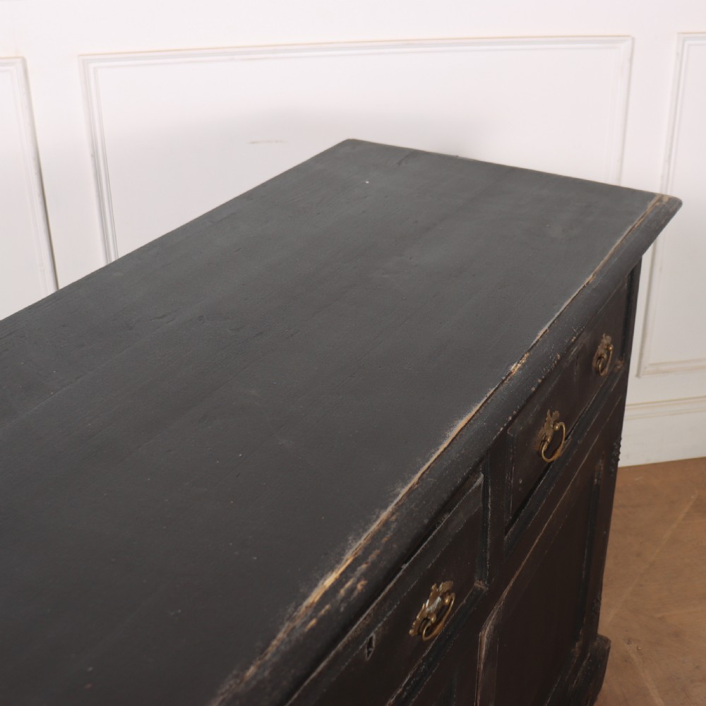 An 18th-century English country dresser base featuring a dark painted finish, three top drawers with brass handles, and three cupboard doors below. View XI