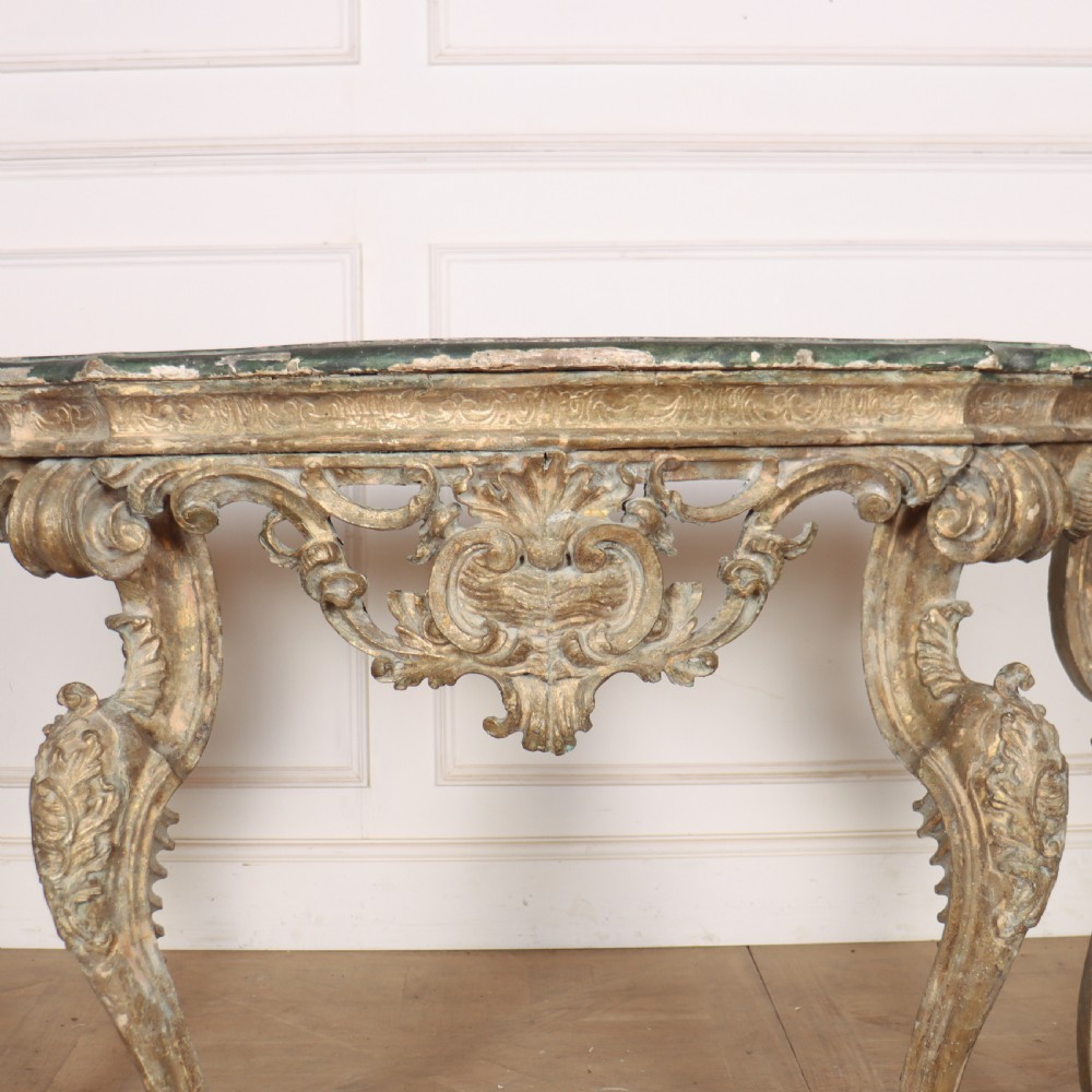 An 18th-century Italian carved giltwood console table featuring scrolled cabriole legs, a rocaille central apron, and a dark green marble top. View IV