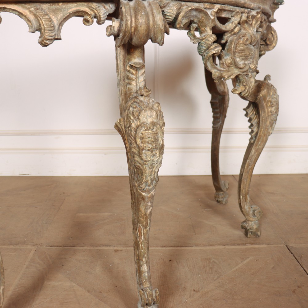 An 18th-century Italian carved giltwood console table featuring scrolled cabriole legs, a rocaille central apron, and a dark green marble top. View VI