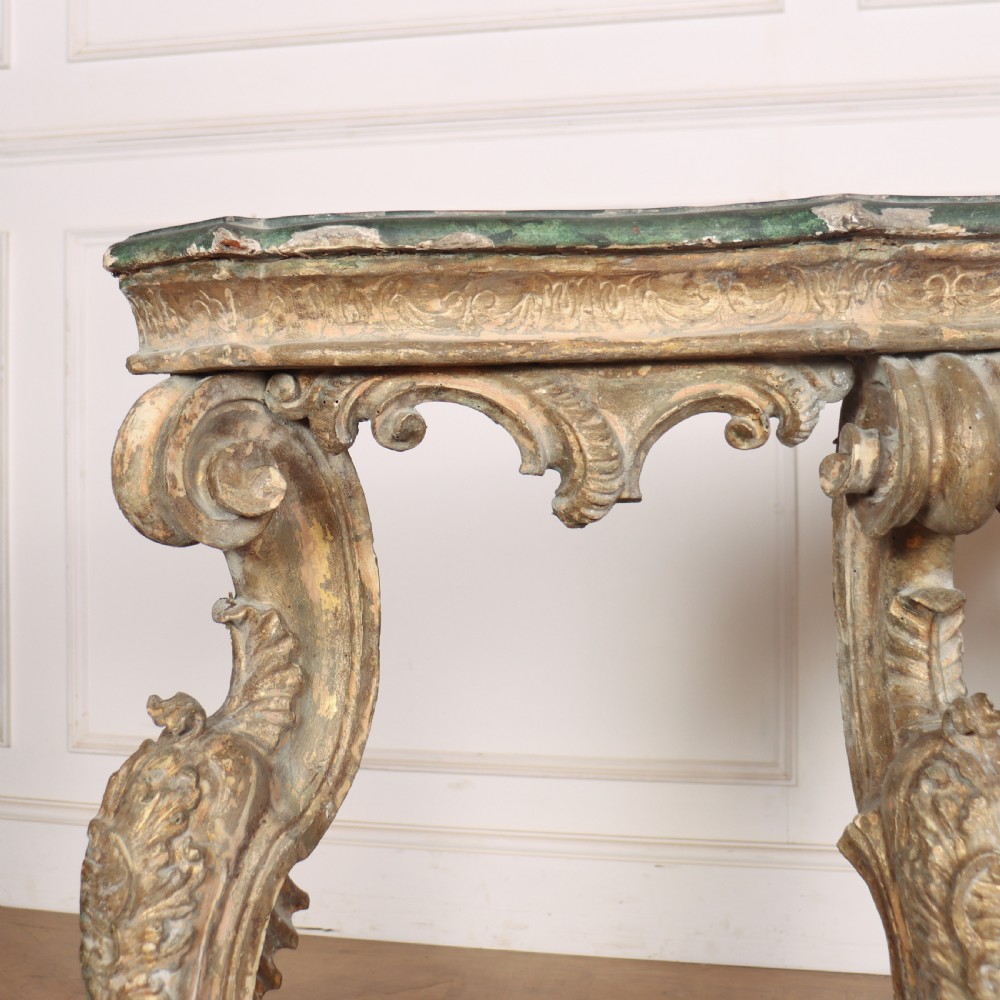 An 18th-century Italian carved giltwood console table featuring scrolled cabriole legs, a rocaille central apron, and a dark green marble top. View VII