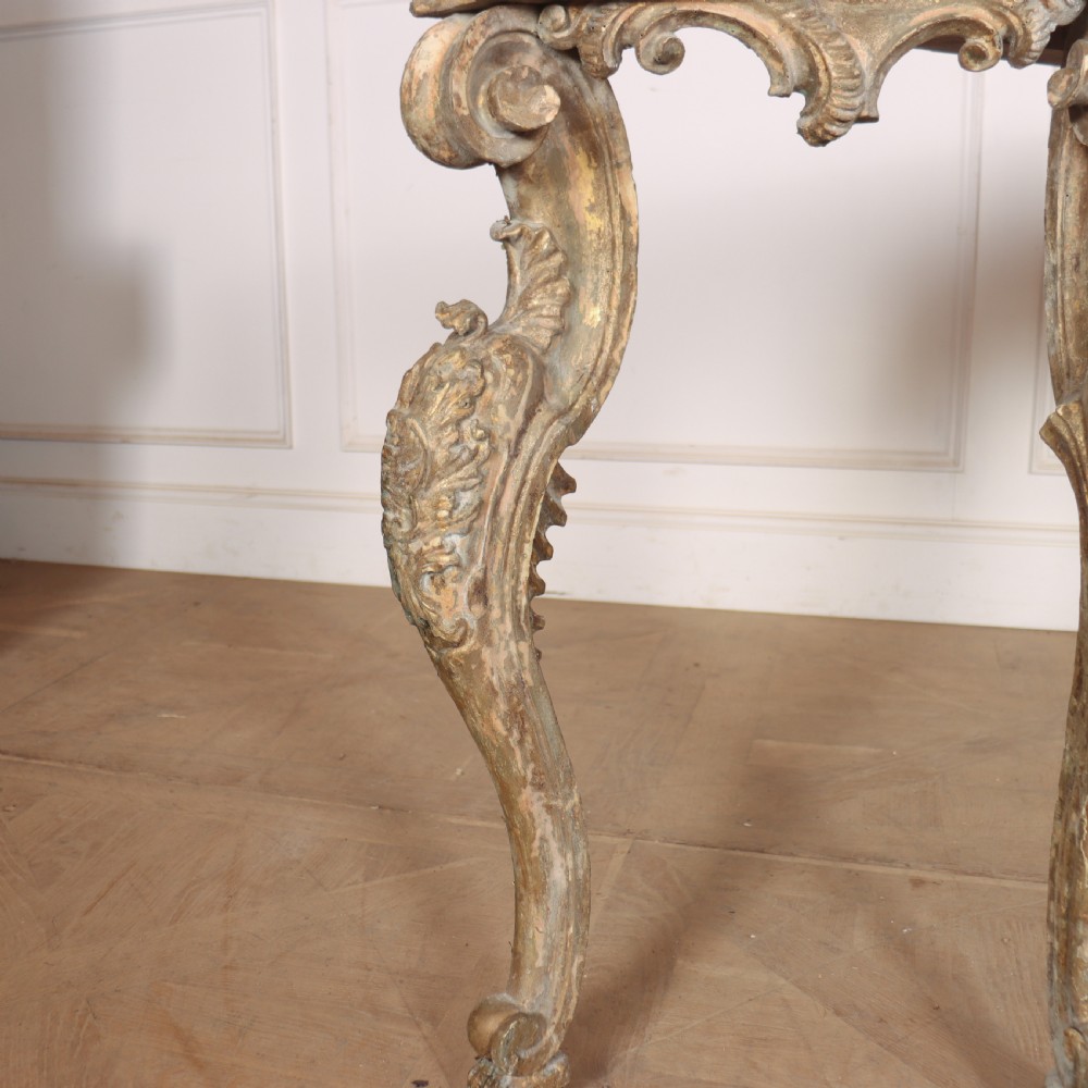 An 18th-century Italian carved giltwood console table featuring scrolled cabriole legs, a rocaille central apron, and a dark green marble top. View VIII
