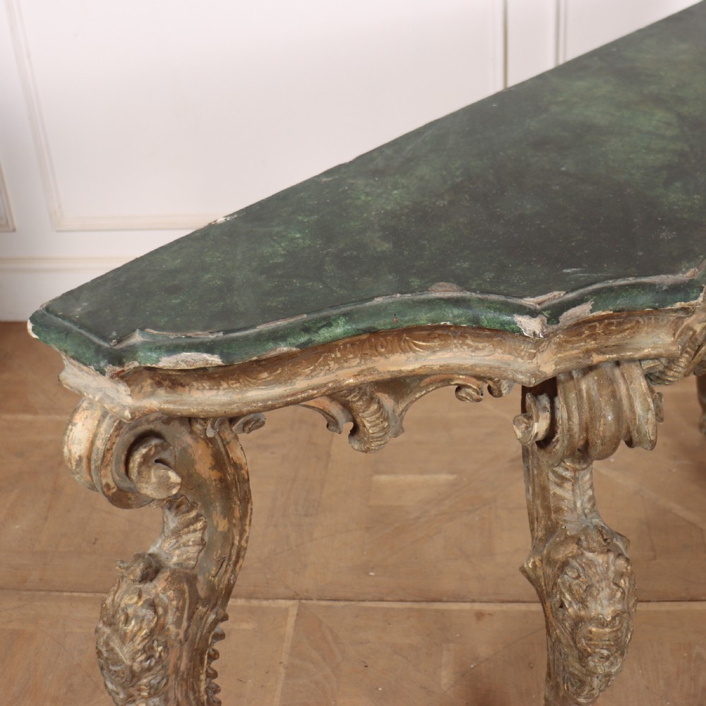 An 18th-century Italian carved giltwood console table featuring scrolled cabriole legs, a rocaille central apron, and a dark green marble top. View IX