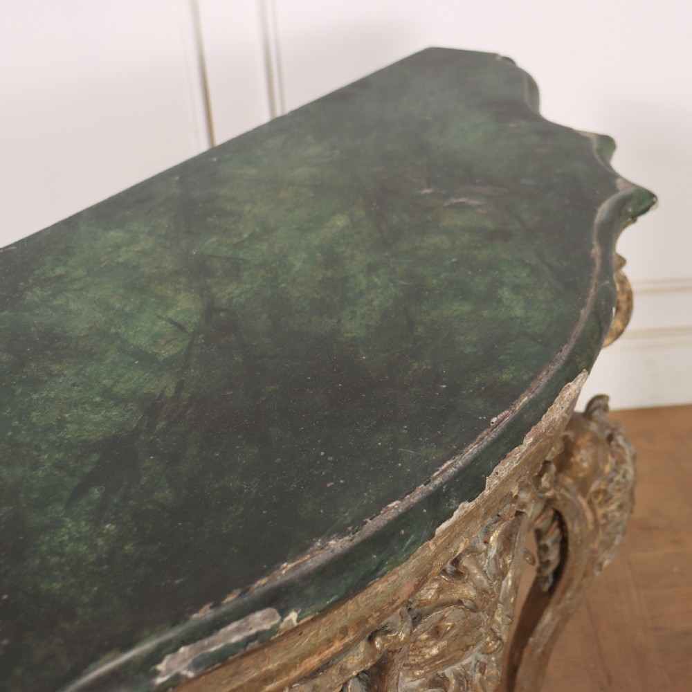 An 18th-century Italian carved giltwood console table featuring scrolled cabriole legs, a rocaille central apron, and a dark green marble top. View X