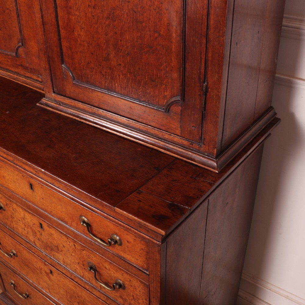 An antique English oak housekeepers cupboard featuring a breakfront upper section with fielded panel doors above a base with multiple drawers and brass hardware. View XIII