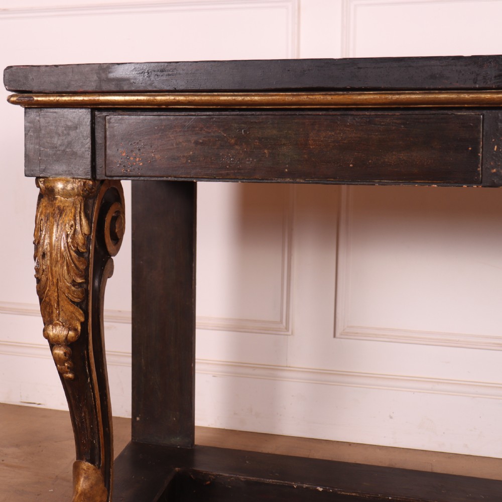 A dark painted and parcel-gilt console table featuring carved acanthus leaf scroll front supports and a flat plinth base. View III
